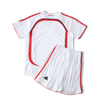 Elite Retro Kits AC Milan 2006/07 away kids football kit in white with red and black accents on a green pitch background