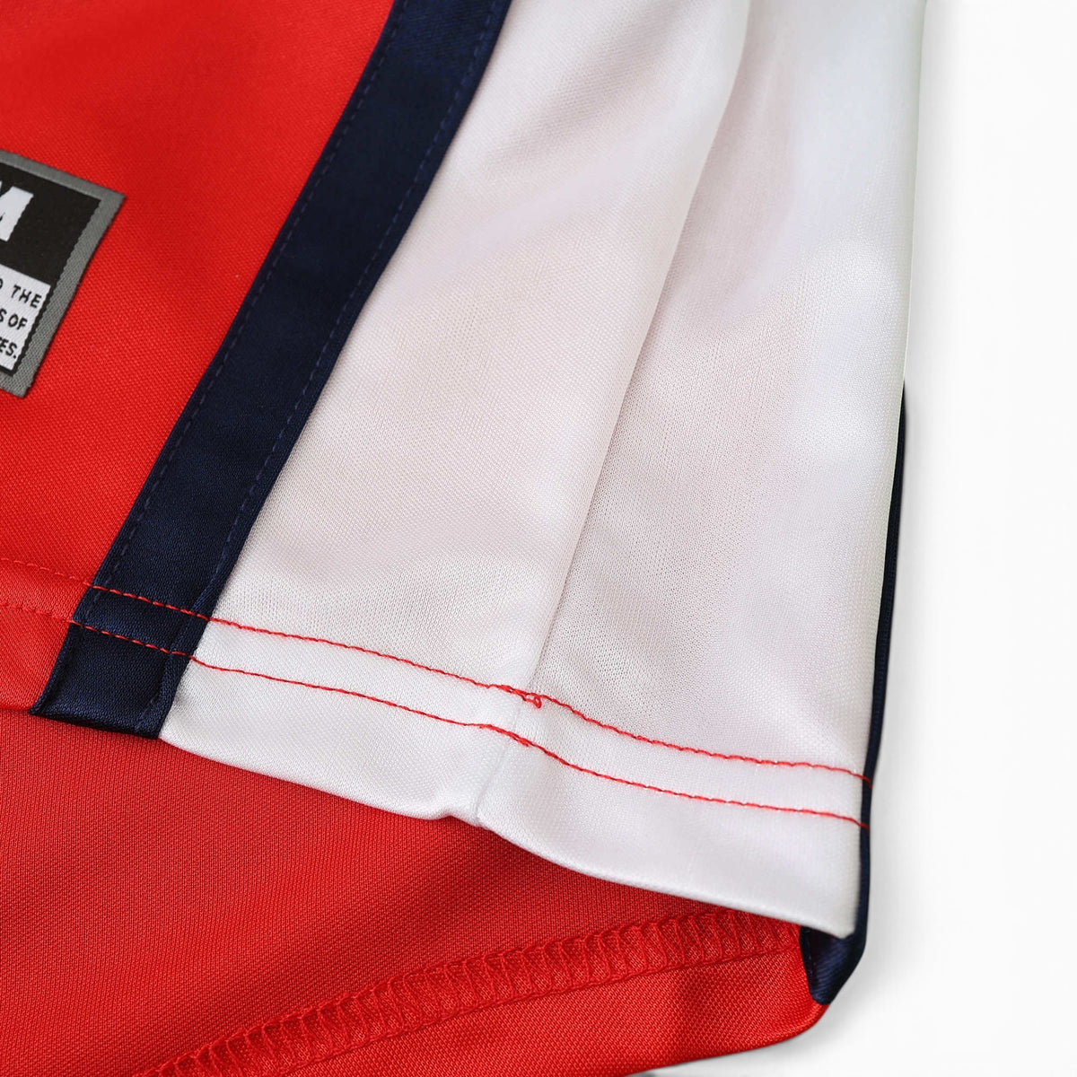 Close-up of Elite Retro Kits Arsenal 1998/99 home shirt sleeve featuring red fabric, white trim, and navy accents.