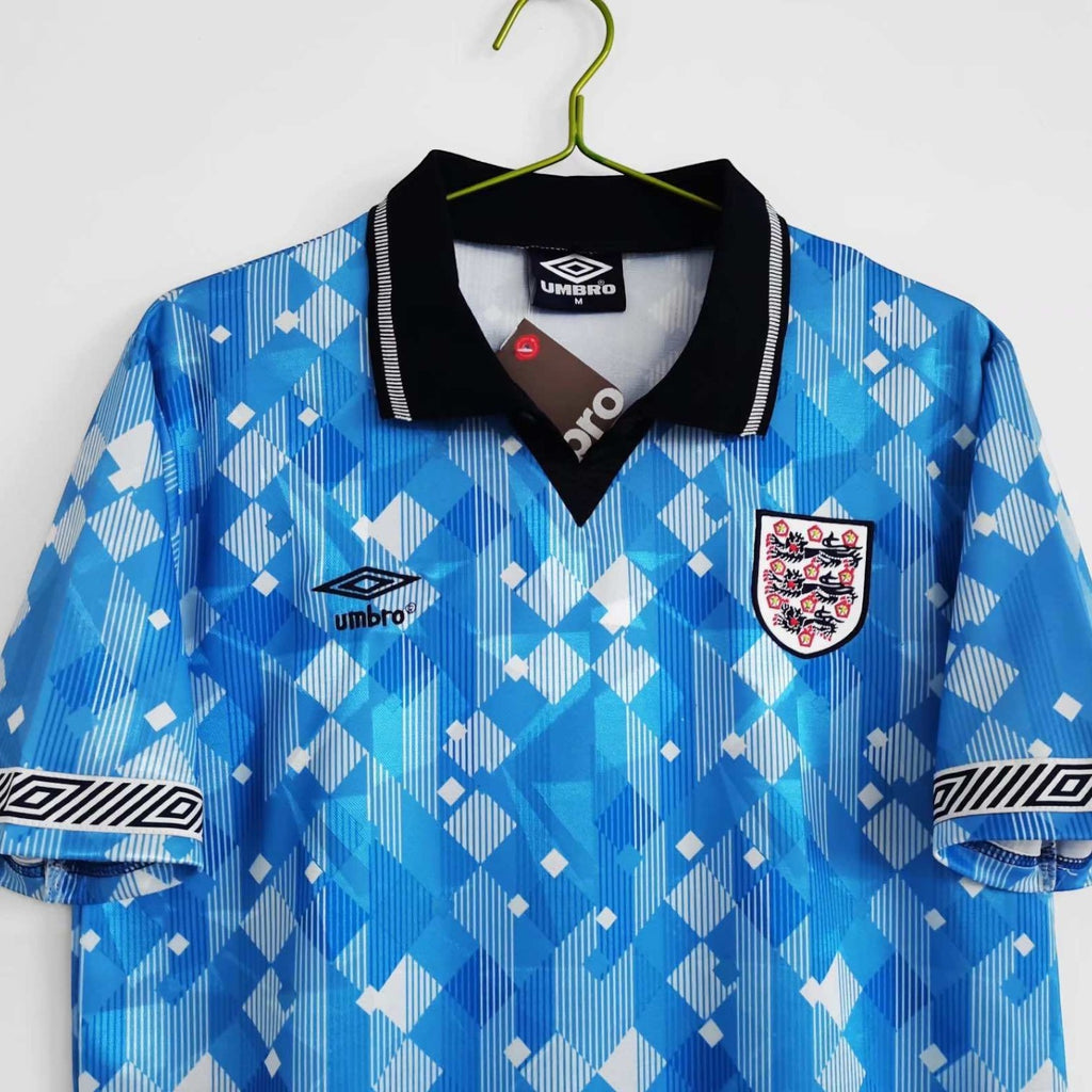 Elite Retro Kits England 1990 third football shirt in blue with geometric pattern, black collar, and Umbro logo.