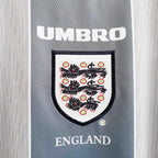 Elite Retro Kits England 1996 away shirt featuring grey-indigo fabric, Umbro logo, and Three Lions crest detail.