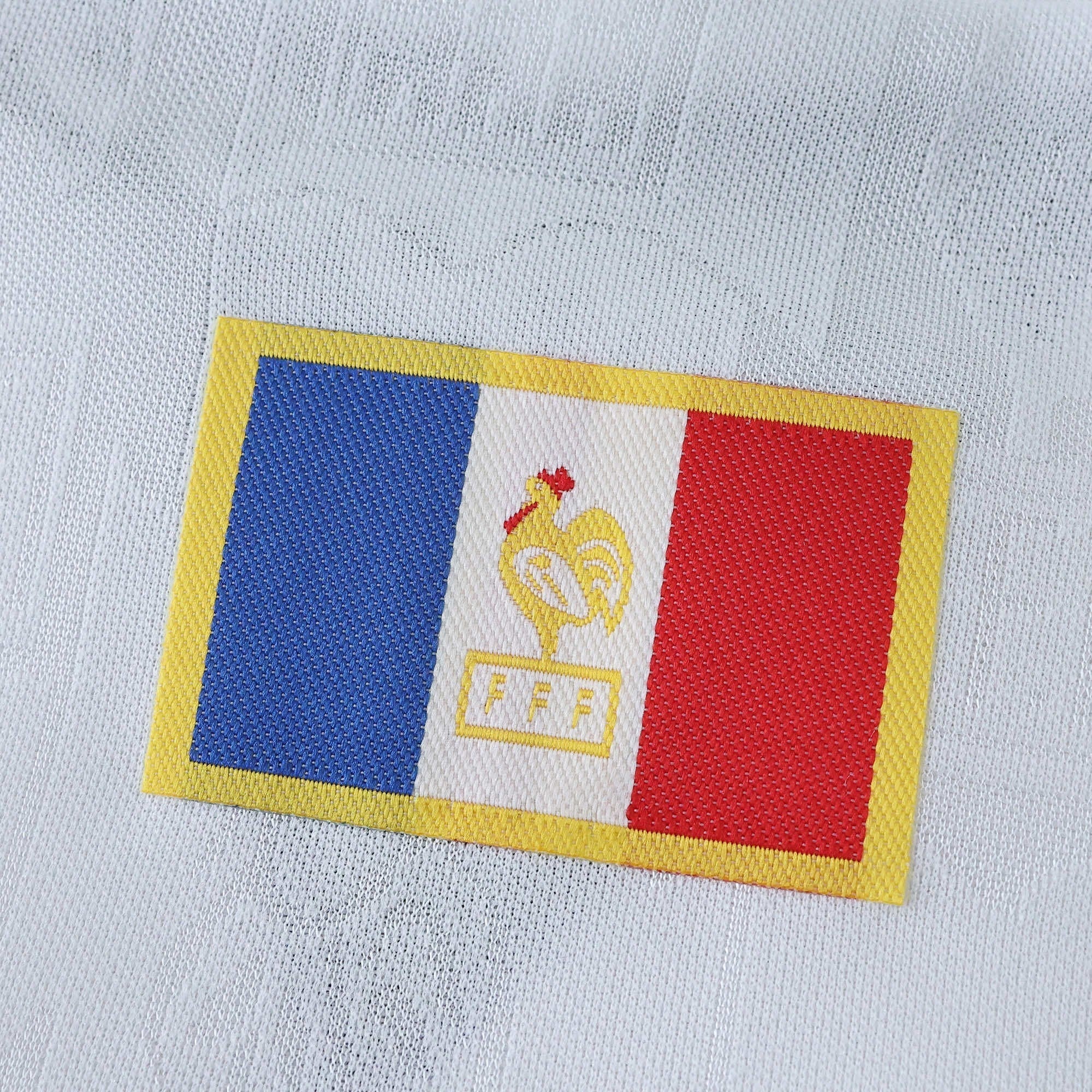 Elite Retro Kits France 1996 away shirt detail featuring the embroidered French flag and cockerel crest on white fabric
