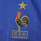 Elite Retro Kits France 2006 home shirt featuring an embroidered cockerel crest and gold star on deep blue fabric.