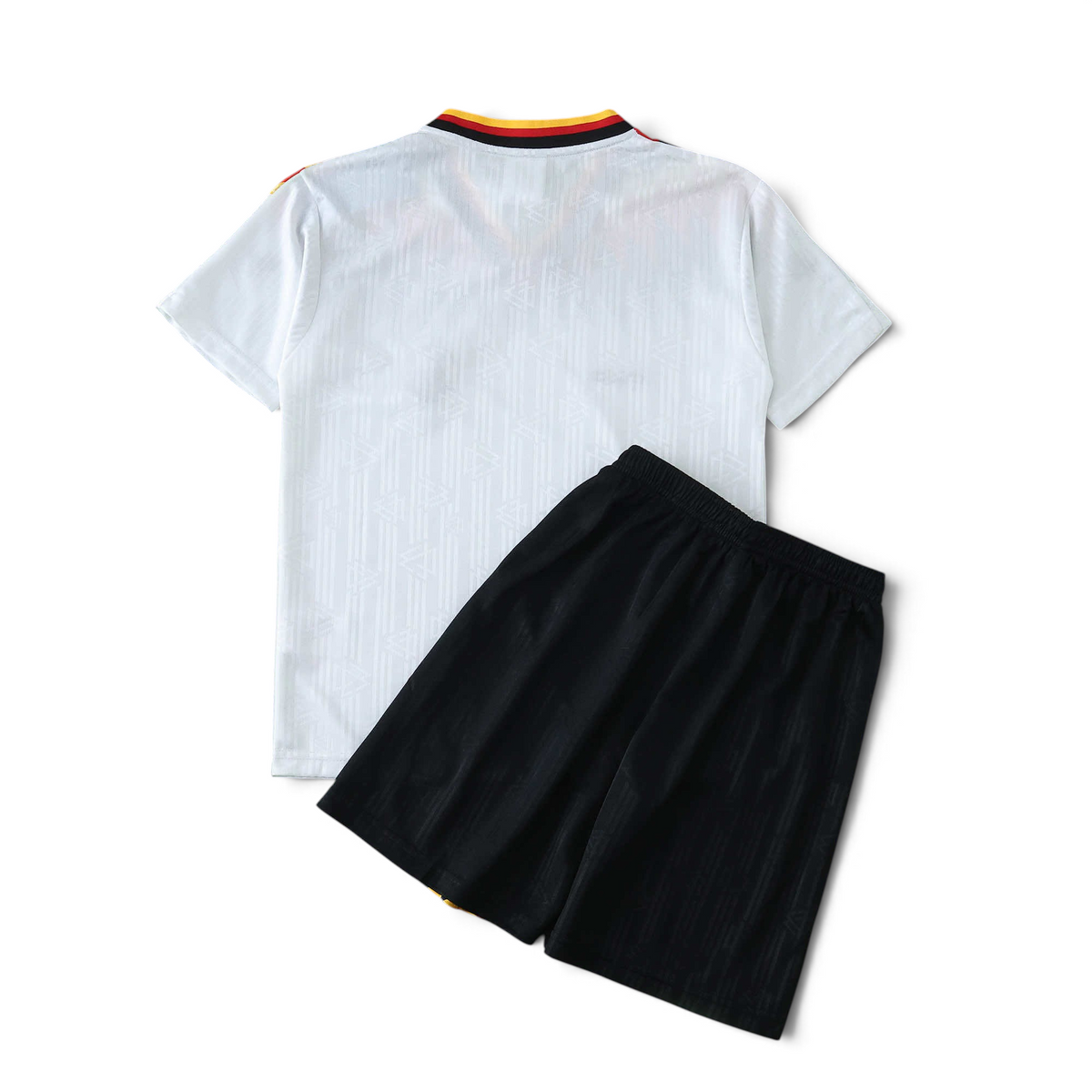 Elite Retro Kits Germany 1994 kids home football kit with white jersey and black shorts on a green pitch background