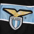 Elite Retro Kits Lazio 1998/99 away shirt detail featuring the embroidered eagle crest on sky blue and black fabric.