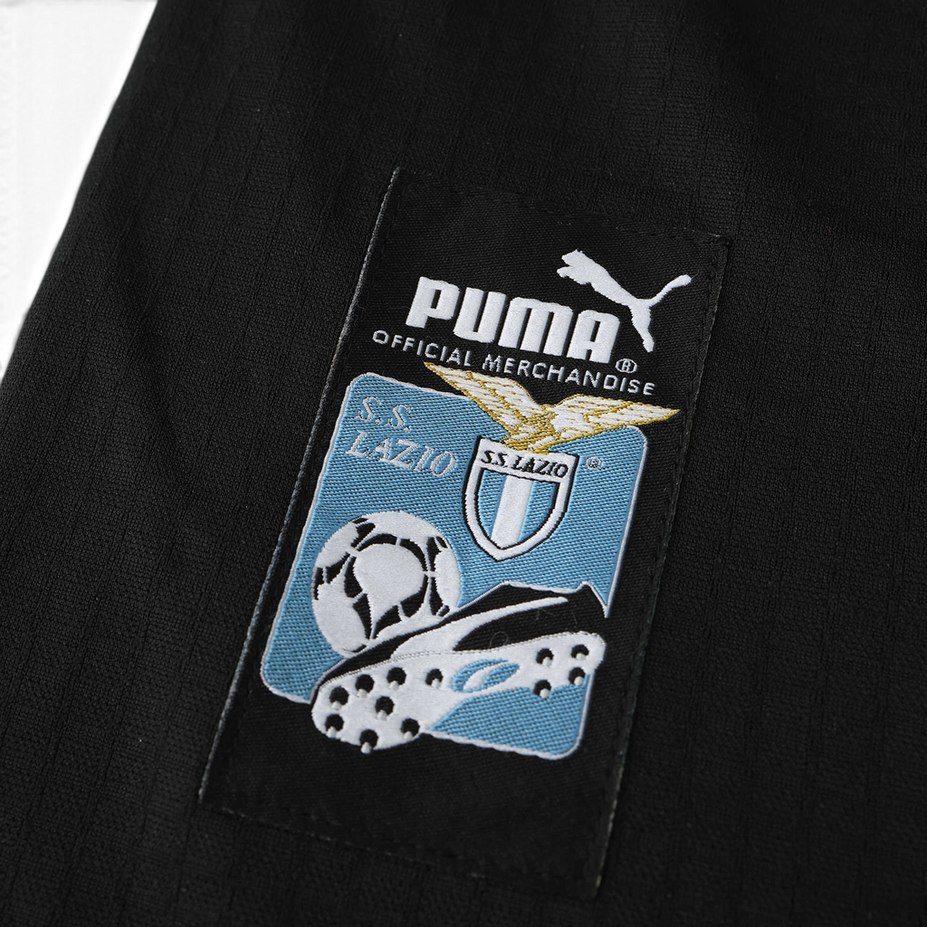 Elite Retro Kits Lazio 1998/99 away shirt detail featuring the embroidered Puma logo and club crest on black fabric.