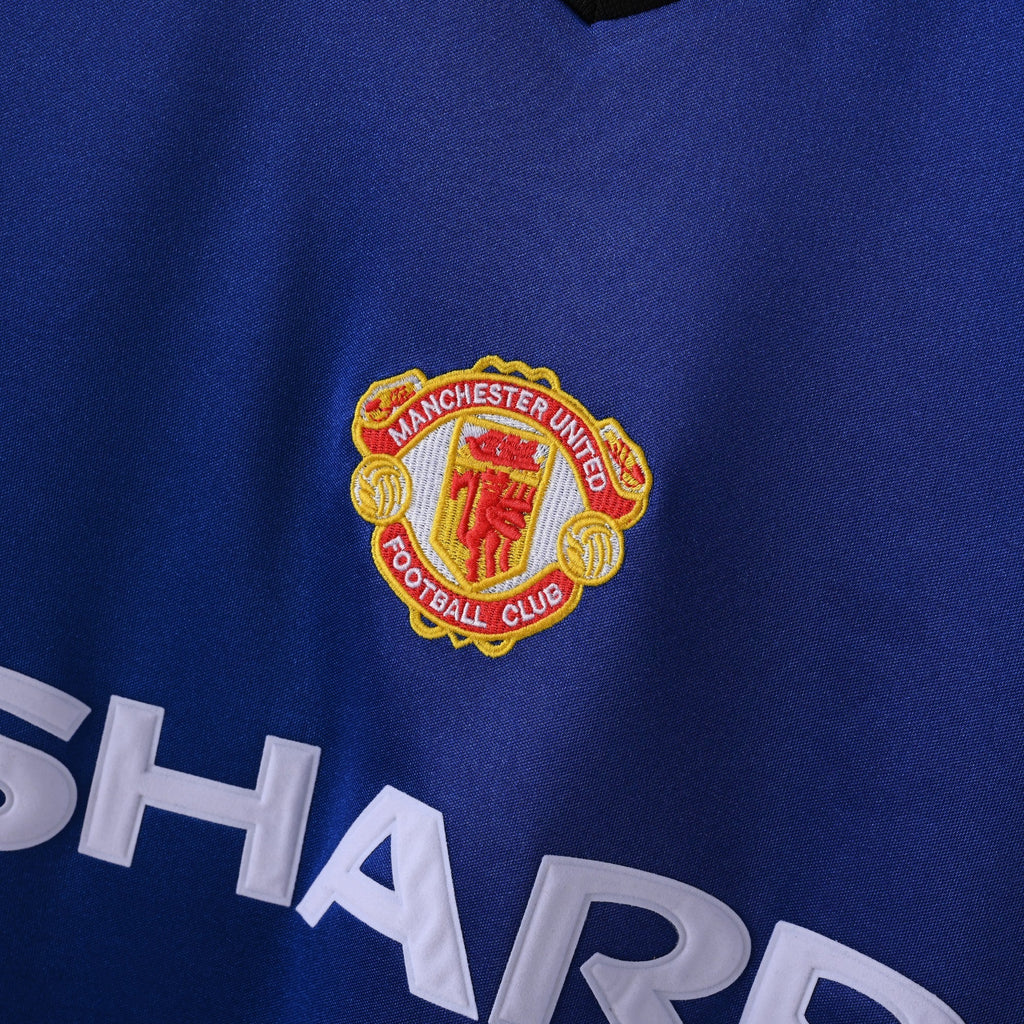 Elite Retro Kits Manchester United 1985/1986 away shirt featuring an embroidered club crest and Sharp sponsor logo.
