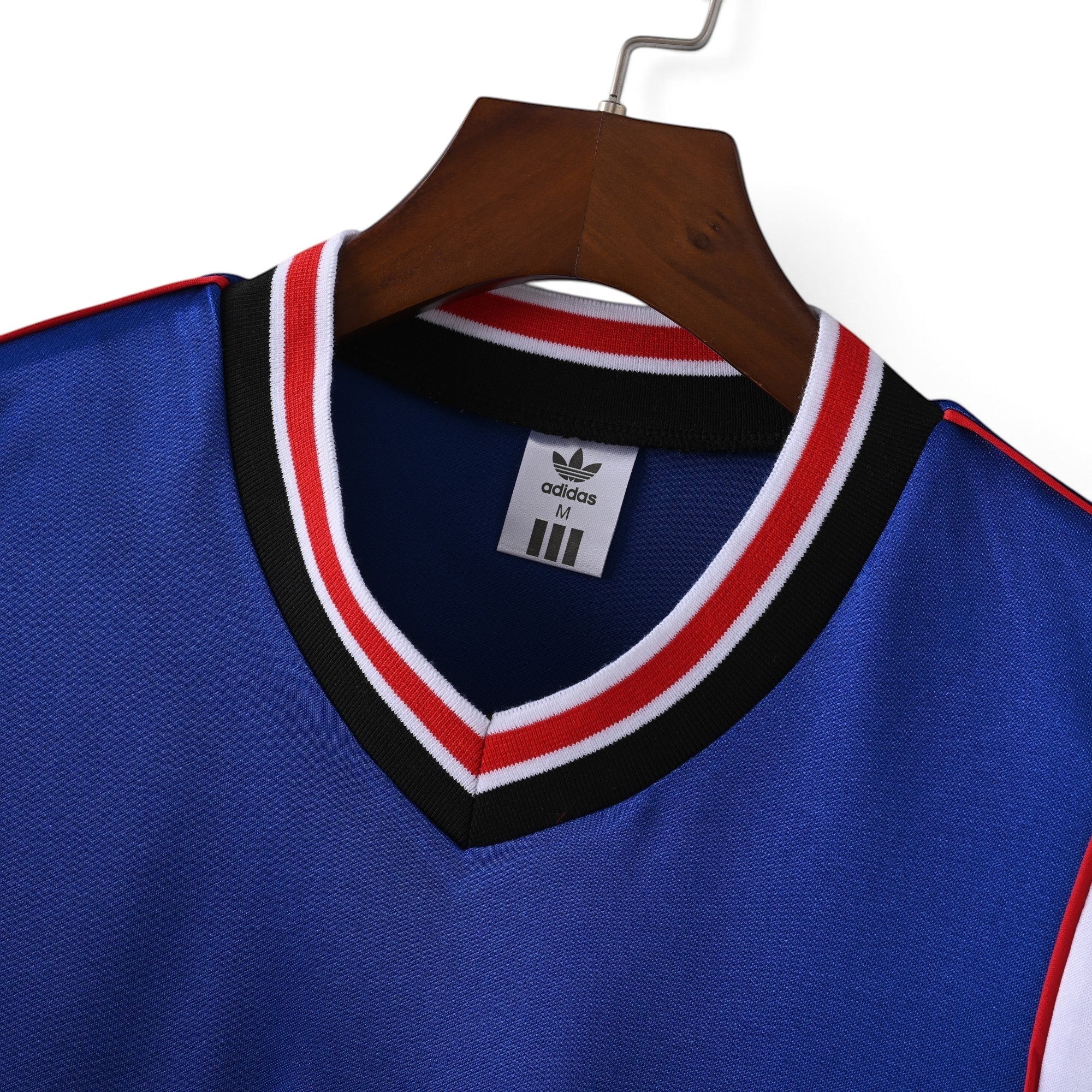 Elite Retro Kits Manchester United 1985/86 away shirt featuring a blue V-neck with red, white, and black striped trim.