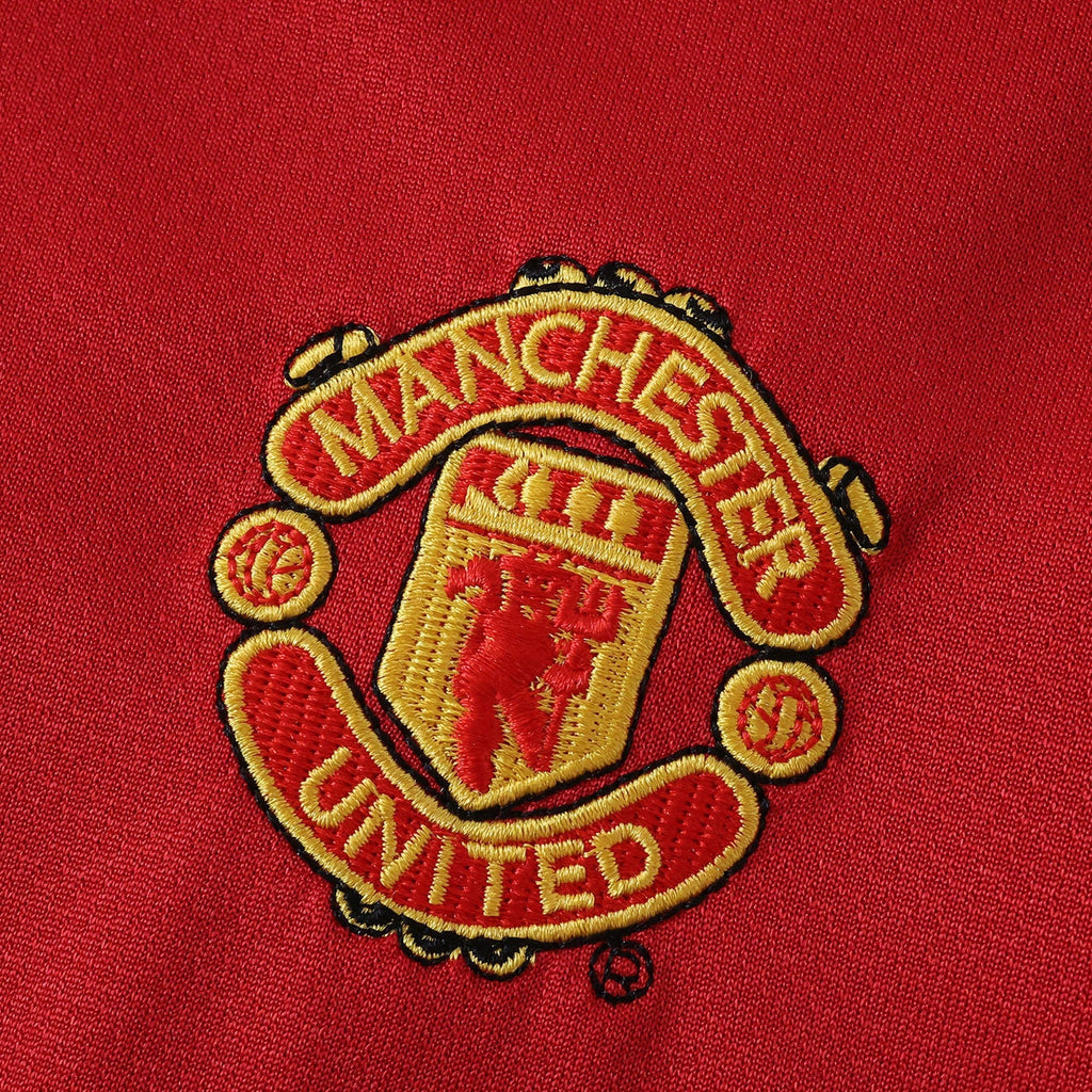 Elite Retro Kits Manchester United 2005/06 kids home kit featuring a detailed embroidered club crest on red fabric.