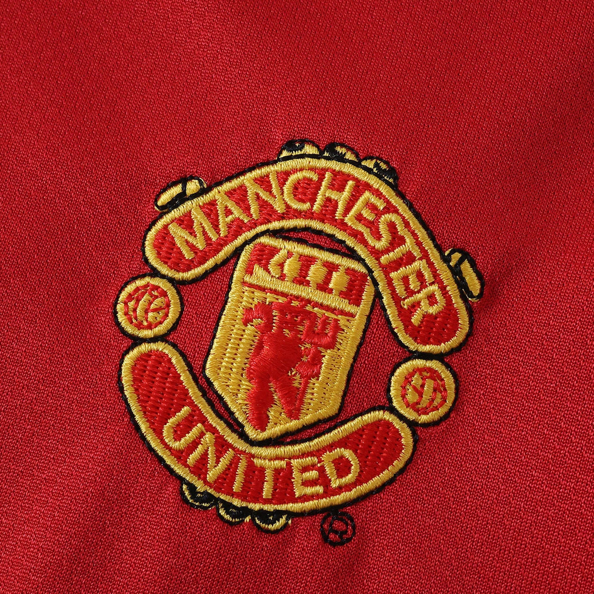 Elite Retro Kits Manchester United 2005/06 kids home kit featuring a detailed embroidered club crest on red fabric.