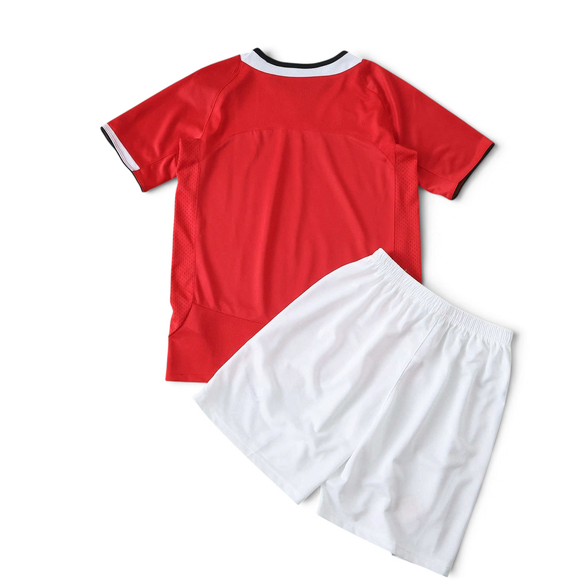 Elite Retro Kits Manchester United 2005/06 kids home kit featuring a red jersey and white shorts on a pitch background.