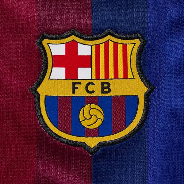 Close-up of an embroidered FC Barcelona crest patch centered on a textured red and blue striped fabric background.
