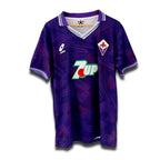 A vintage soccer jersey in purple with a geometric pattern, featuring the original Lotto logo, a collar, and 7UP sponsor branding.