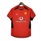 Red sports jersey with black accents on a hanger, featuring Vodafone and Nike logos.