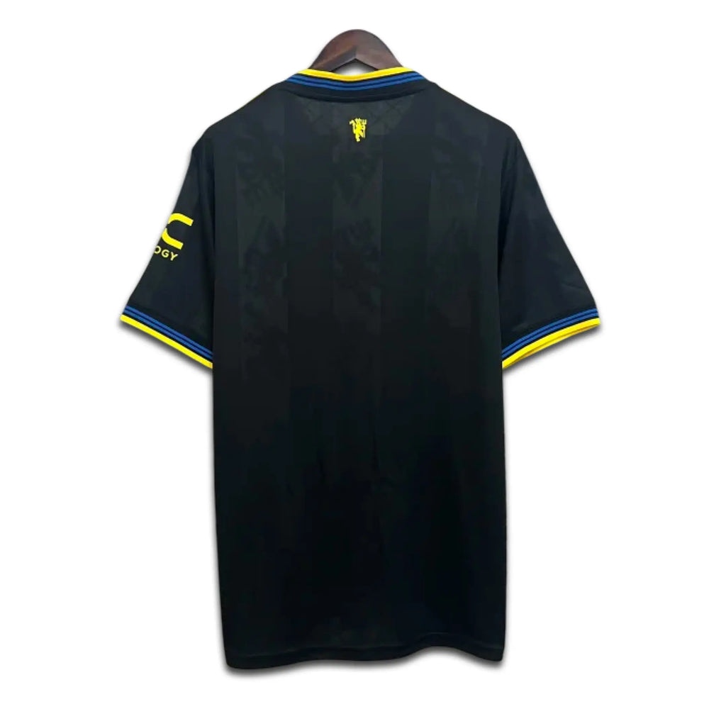 Black Manchester United shirt with yellow accents on a hanger against a white background