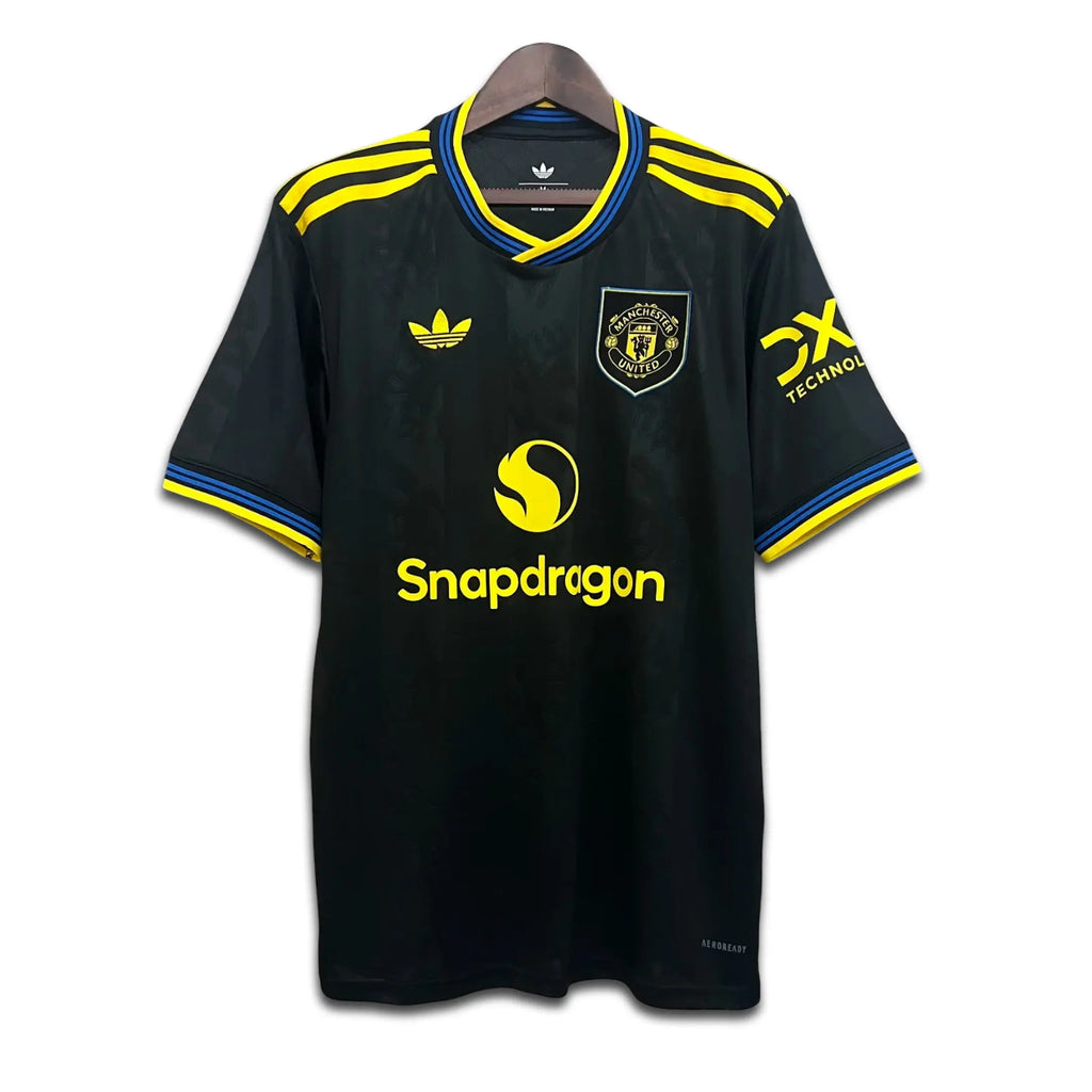 Black Manchester United jersey with yellow accents and brand logos on a white background