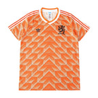 Orange and white Adidas Netherlands soccer jersey with a geometric pattern, featuring the Adidas logo and the lion crest with 'NEDERLAND' on the chest.