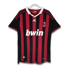A soccer jersey with red and black stripes, featuring the Bwin sponsor logo and Adidas branding.