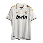 A white Real Madrid home shirt from the 2011/12 season with subtle gold trim and the Bwin sponsor logo.