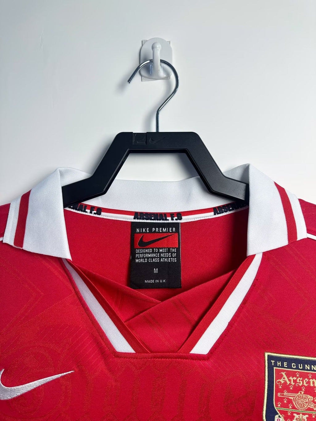 Red sports jersey with a Nike tag on a hanger against a white background
