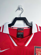 Red sports jersey with a Nike tag on a hanger against a white background