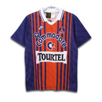 A short-sleeved soccer jersey with a bold red stripe design, blue and orange solid colors, and the Commodore sponsor logo across the chest.