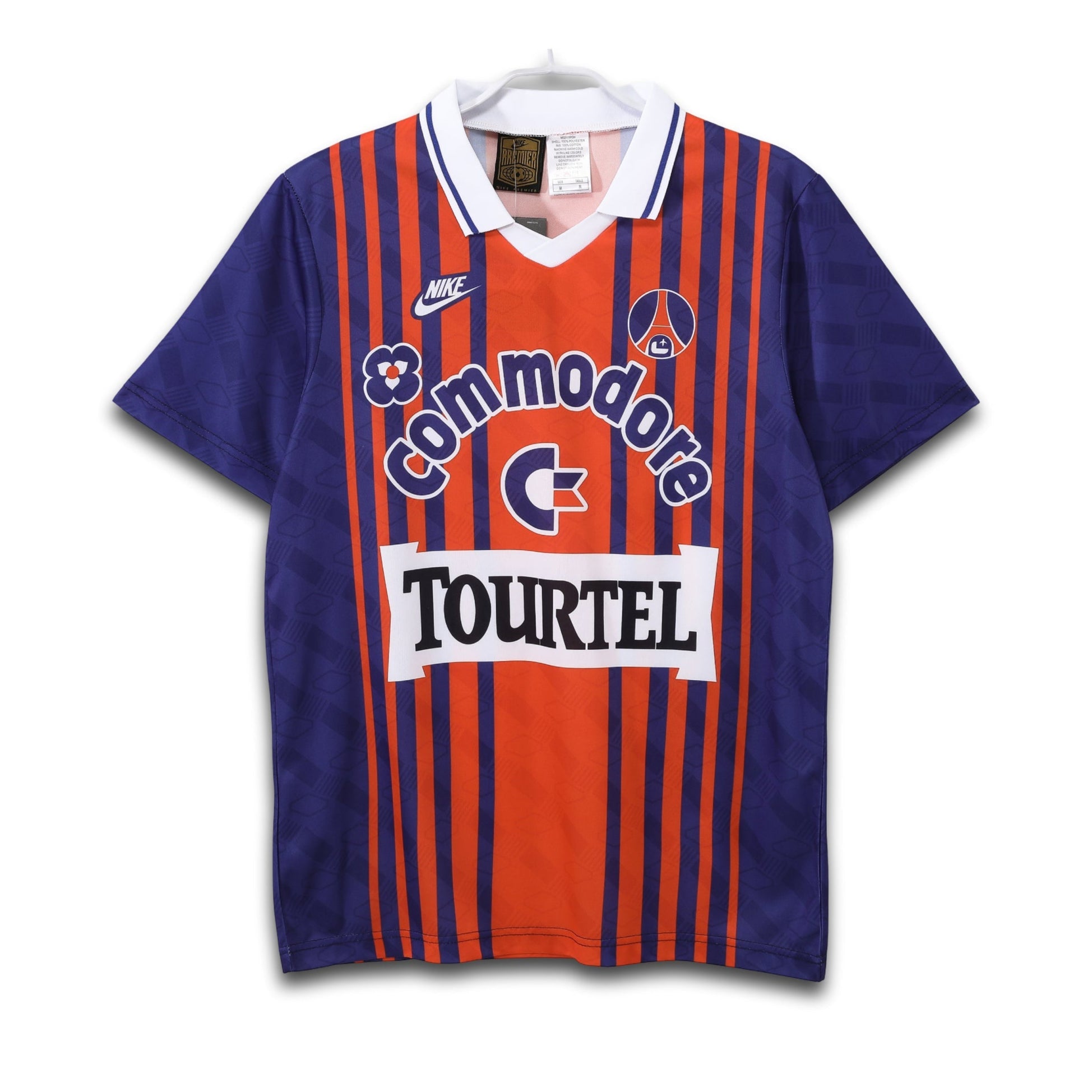 A short-sleeved soccer jersey with a bold red stripe design, blue and orange solid colors, and the Commodore sponsor logo across the chest.