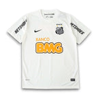 A white Nike Santos FC soccer jersey with black and yellow accents, featuring the 'Netshoes' sponsor logo on the sleeves, 'Banco BMG' on the front, and the club crest on the chest.